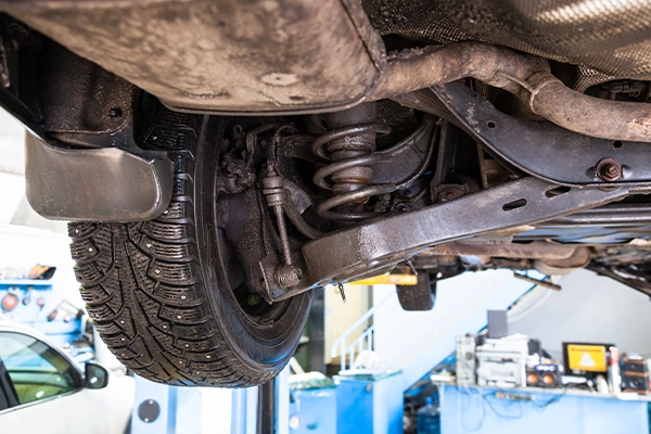 Close-up of suspension system of vehicle on lift